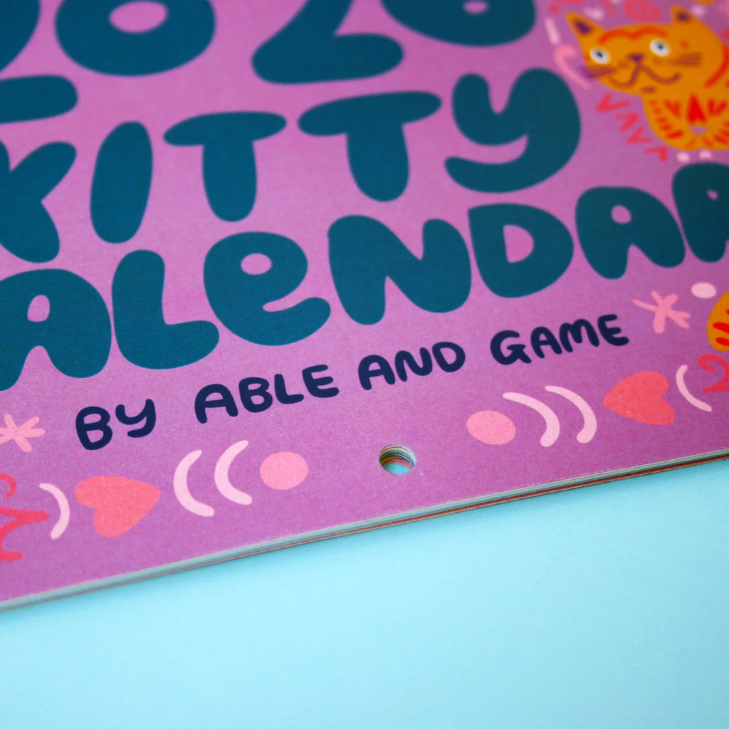 Purple calendar cover with blue text and colorful illustrations on a light blue background