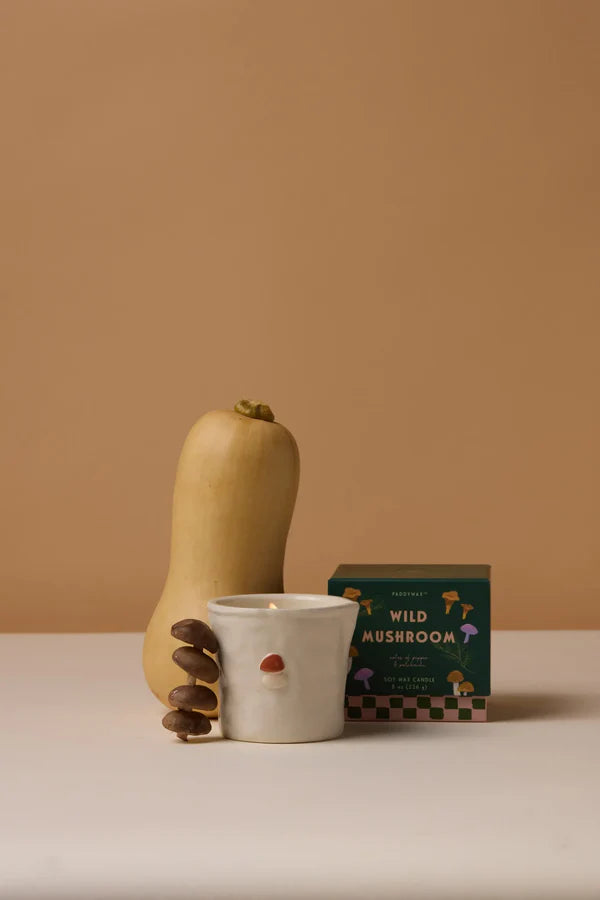 Butternut squash, small white cup with a red dot, and a box labeled 'Wild Mushroom' on a beige surface.