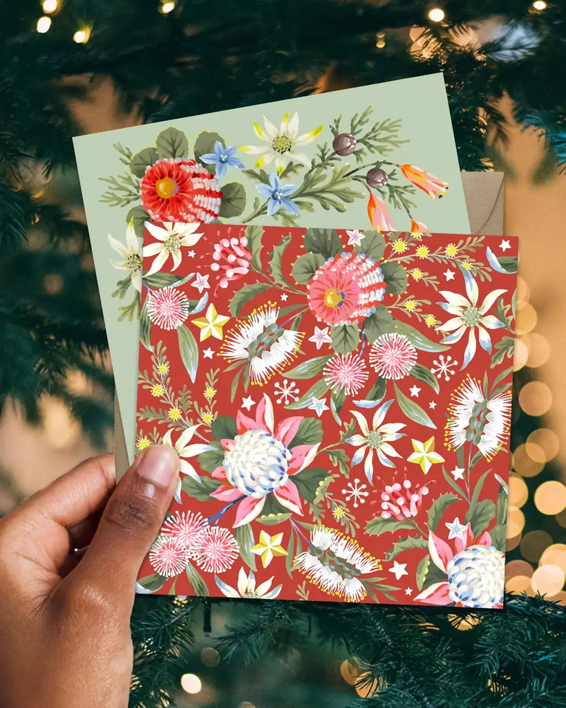 Floral-patterned cards held in front of a decorated Christmas tree.