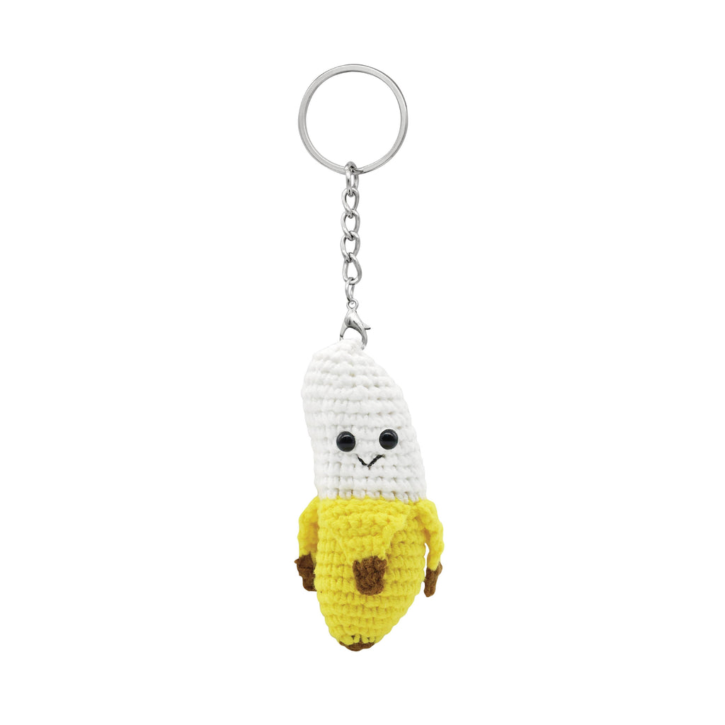 Crocheted keychain shaped like a banana with a face on a white background