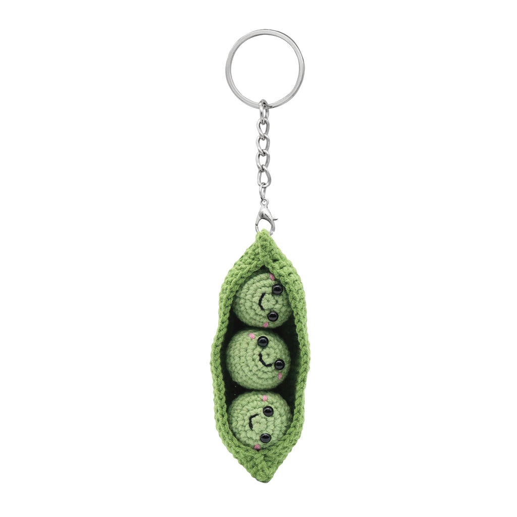 Green crochet pea pod keychain with three peas on a white background