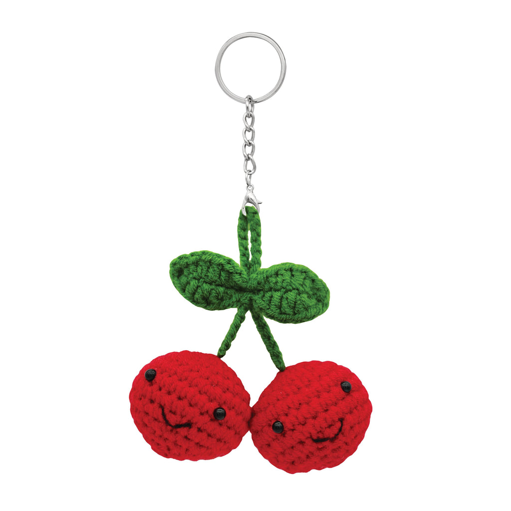 Crocheted cherries with green leaves on a keychain against a white background