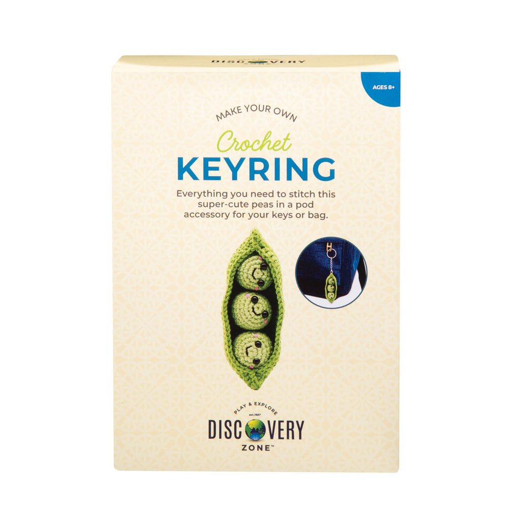 Packaging for a crochet keyring kit with peas in a pod design on a beige background.