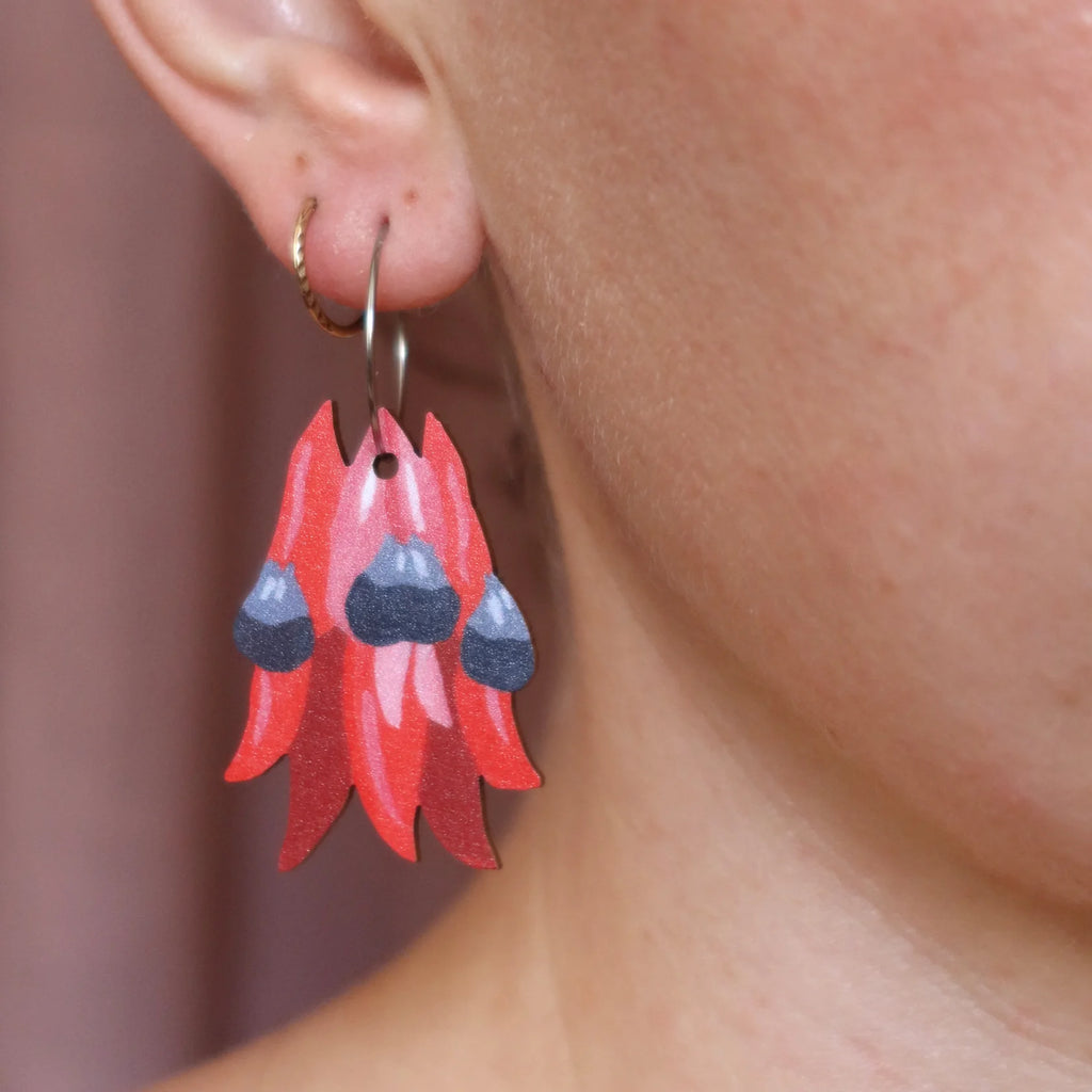 Red floral earrings worn by a person with a blurred background